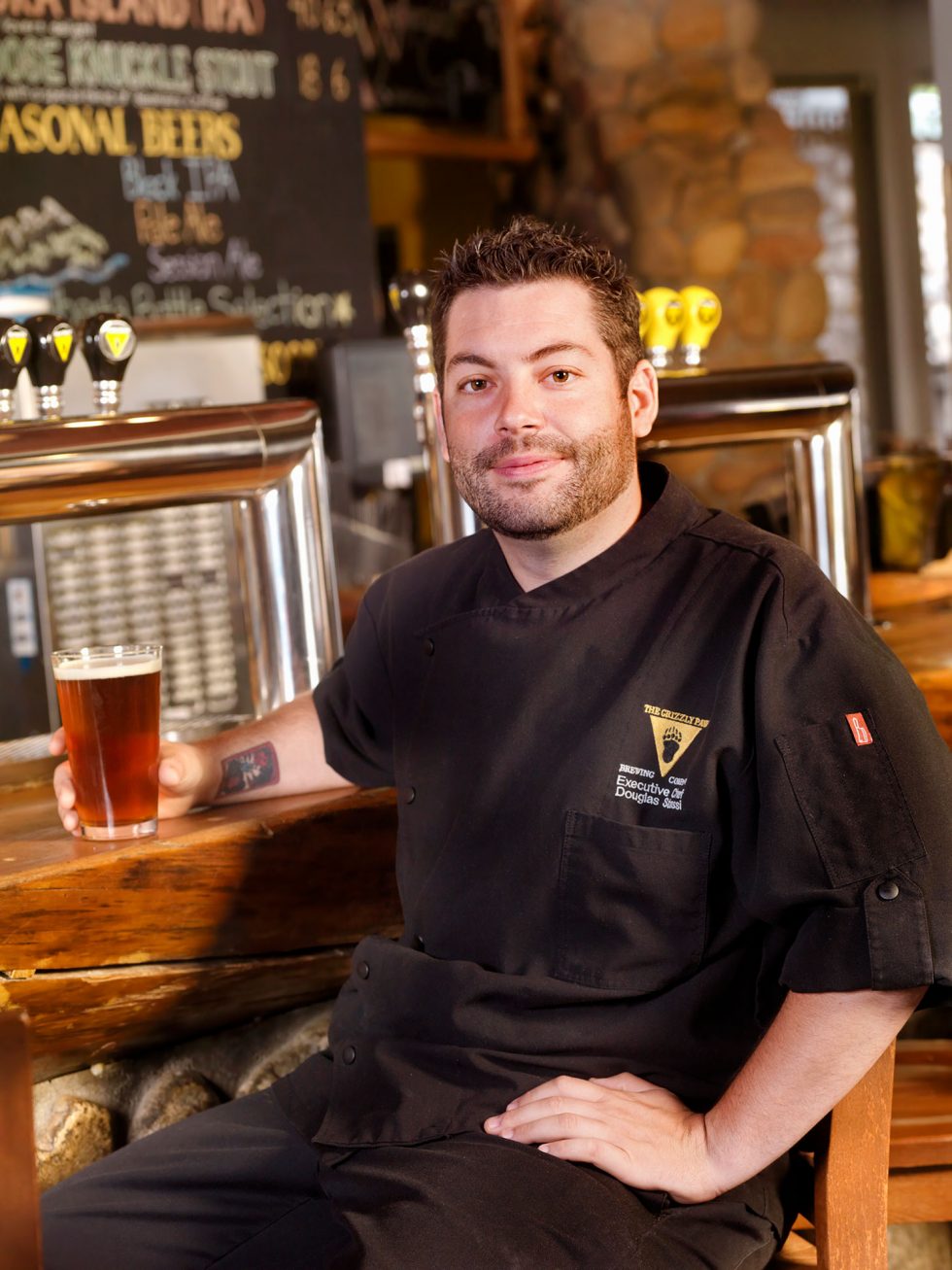 Calgary People Photographer. Chef sitting at Grizzly Paw bar with beer in hand.